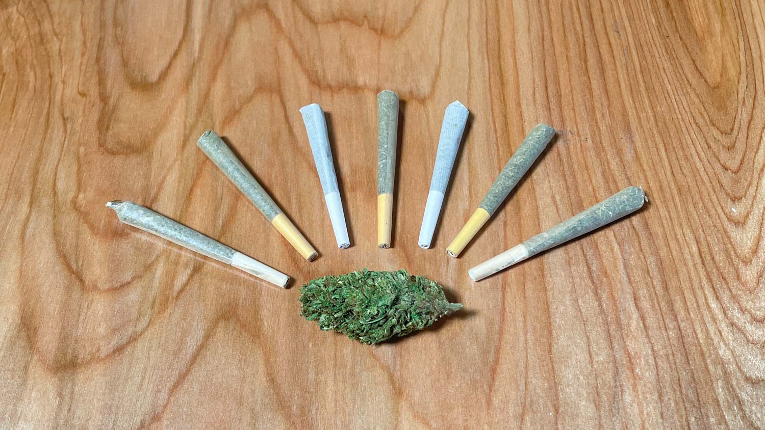 An image of seven perfect pre-rolls and a CBD cannabis bud