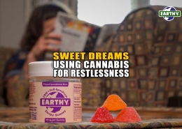 Person reads on a couch preparing to relax and fall asleep. Jar of Earthy Now CBN gummies in the foreground. Cannabis relates to restlessness and sleep. Earthy Now