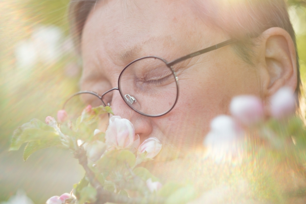 Person smelling flowering plants, related to assessing the environmental impact of cannabis cultivation