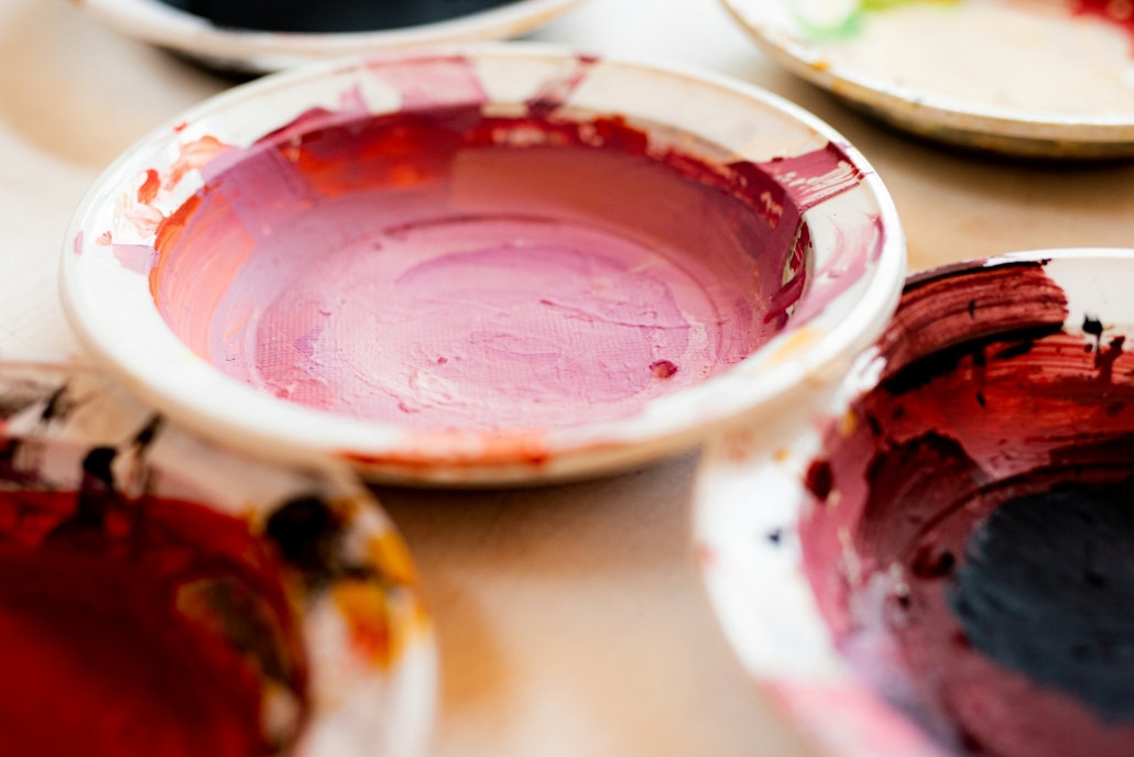 Small bowls in an art studio have dried paint in them. Cannabis and creativity are related through art, music and writing. 